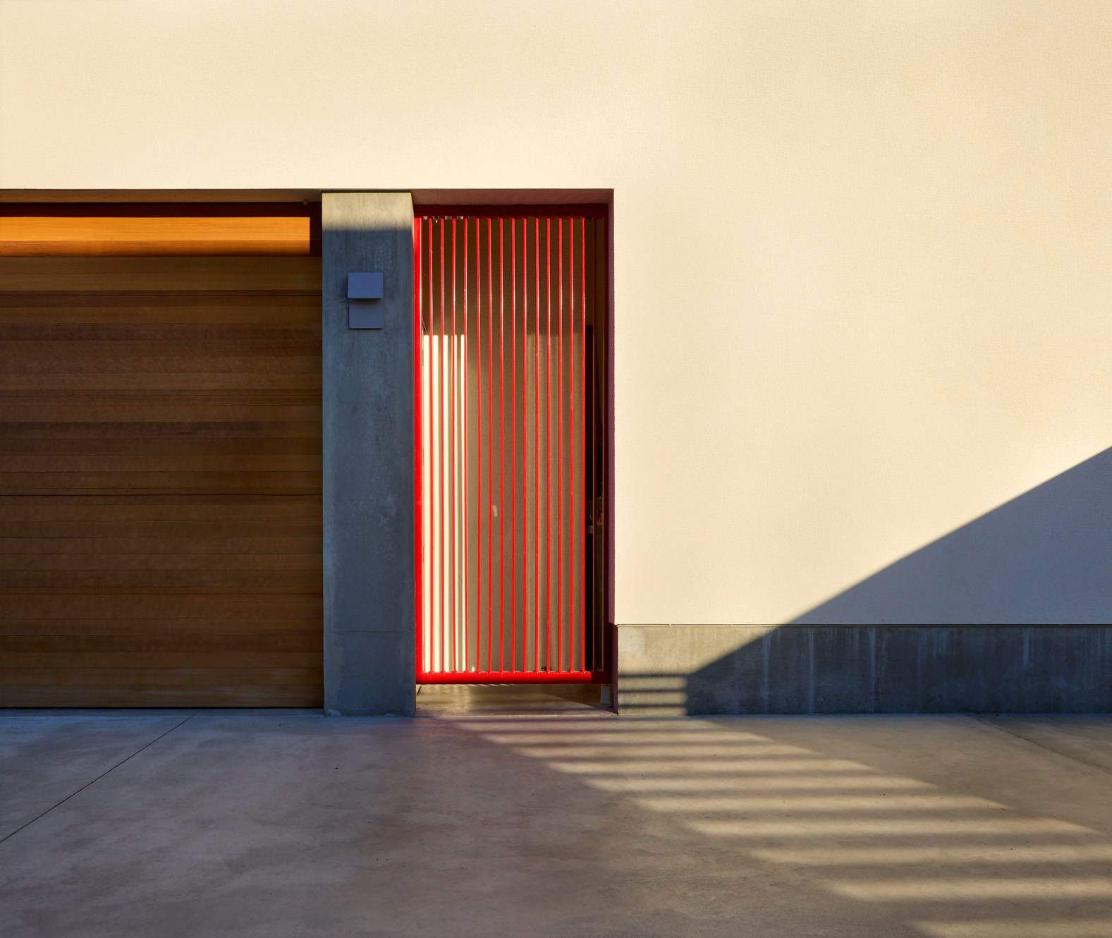 Detail Of Modern Garage Door And Red Gate With Afternoon Shadows