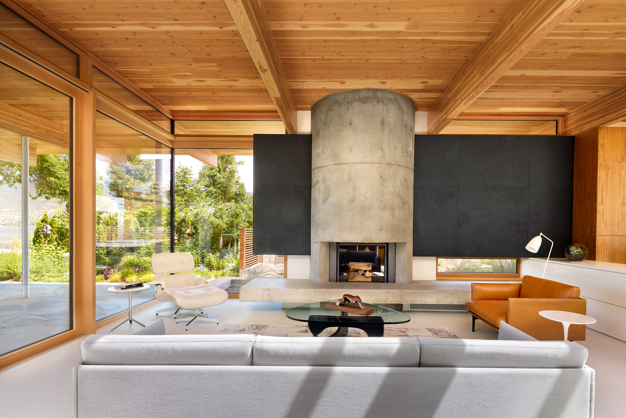 Interior view of modern residence living room with wood ceiling and circular concrete fireplace