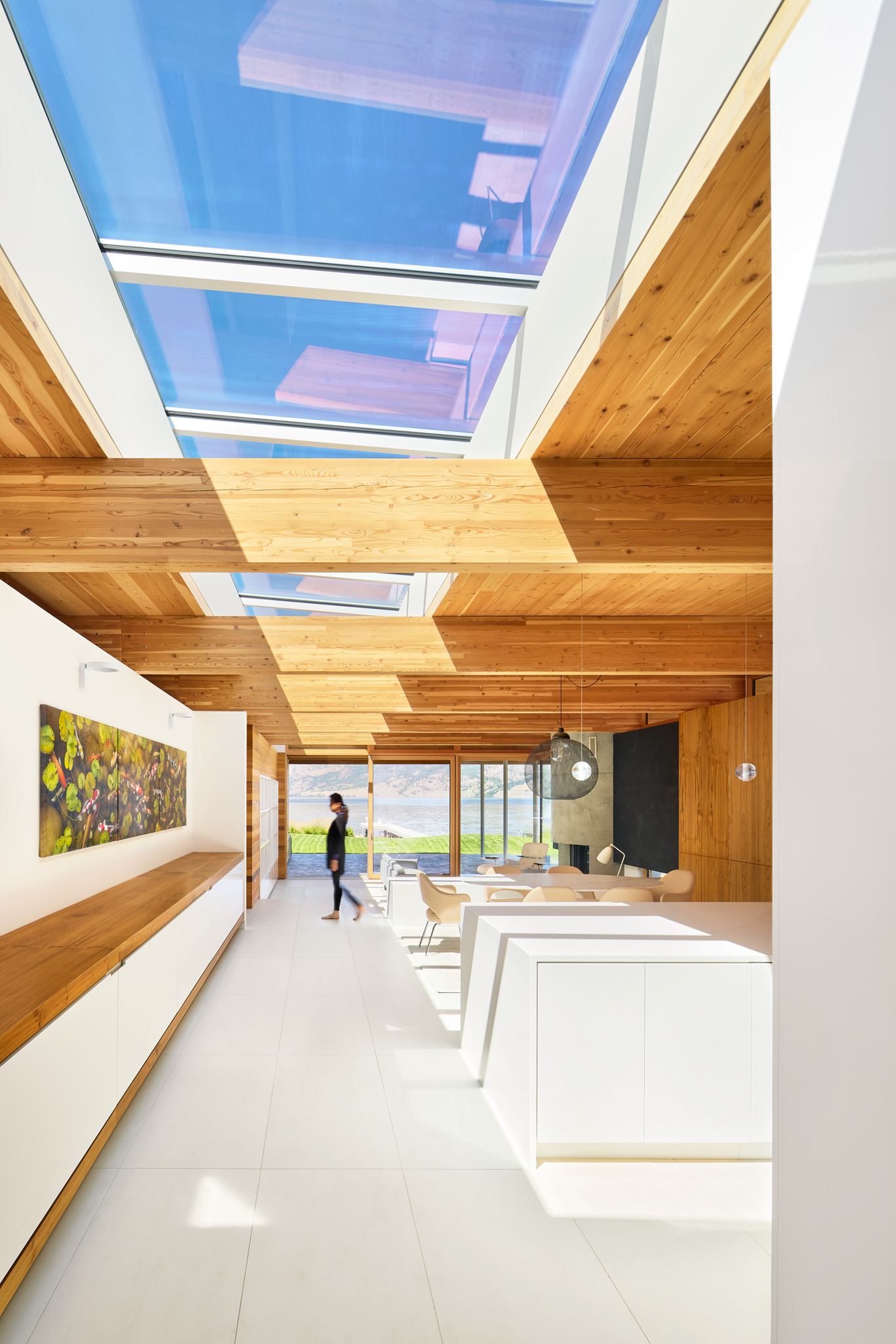 Interior view of modern bright home with blue skylights and view out to lake